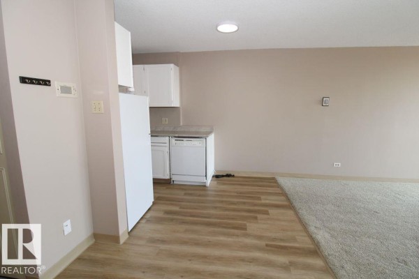 View of the kitchen area with white appliances, white cabinets, and light wood-look flooring. - #408 10883 Saskatchewan Dr Nw, Edmonton