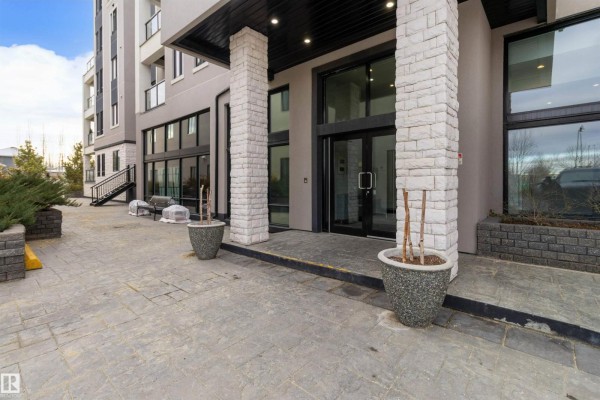 Building lobby with marble walls, dark carpet, stairs with patterned risers, an elevator, and modern lighting. - #408 1350 Windermere Wy Sw, Edmonton