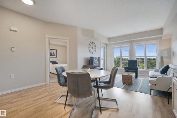 Living and dining area with entrance to bedroom, view of trees through windows. - #408 45 Inglewood Dr, St  Albert