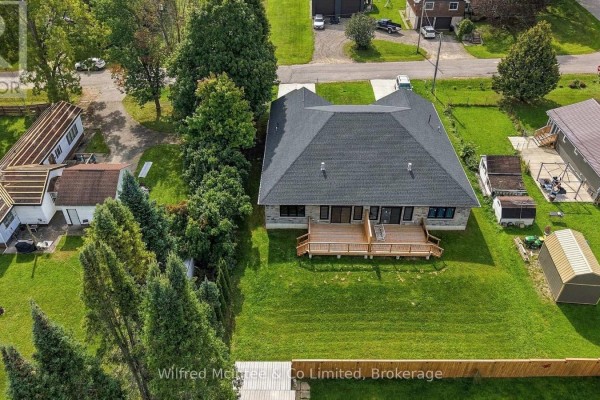 The backyard deck with stairs and black metal balusters connects to the house's stone exterior. - 408 Alma Street, Arran Elderslie