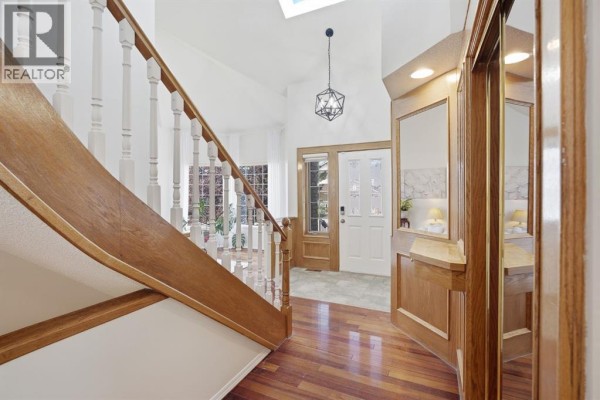 View of the entrance foyer with a wooden staircase, white walls, and wood trim. - 408 Hawkland Place Nw, Calgary
