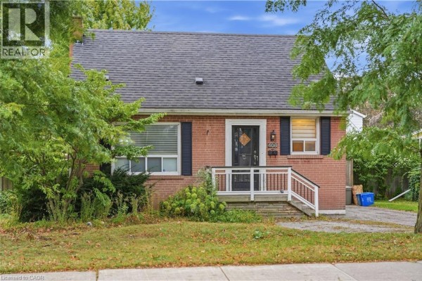 Front view of a red brick bungalow with a walkway, porch, and overgrown landscaping. - 408 Sanatorium Road, Hamilton