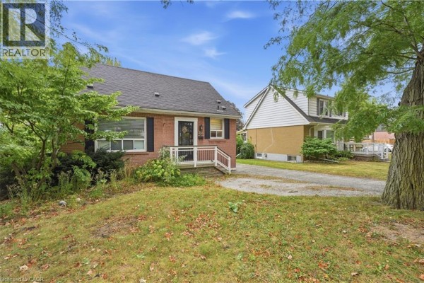 View of the red brick bungalow from the right side, with a neighbor's house visible. - 408 Sanatorium Road, Hamilton