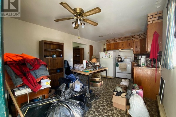 Messy kitchen with wooden cabinets, white appliances, a ceiling fan, and a cluttered dining table. - 408 Silver Queen Lake Road, Cochrane