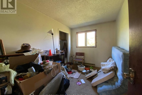 Cluttered bedroom with a mattress on the floor, a window, and a doorway to a closet. - 408 Silver Queen Lake Road, Cochrane