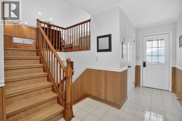 Interior entryway with a wooden staircase, white doors, and wood-paneled walls. - 4084 Bluepoint Drive, Plympton Wyoming