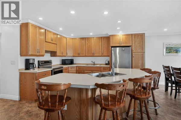 Kitchen with light wood cabinets, a large island with bar stools, and stainless steel appliances. - 4084 Bluepoint Drive, Plympton Wyoming