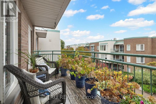Balcony with wicker chairs and potted plants overlooks the courtyard. - 408a - 62 Donald Street, Ottawa