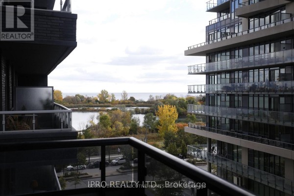 Balcony view of water, trees with autumn foliage, and adjacent modern buildings. - 409 - 110 Marine Parade Drive, Toronto