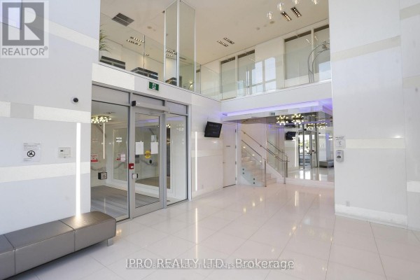 Bright building lobby with glass doors, polished white floors, and mirrored ceiling. - 409 - 110 Marine Parade Drive, Toronto