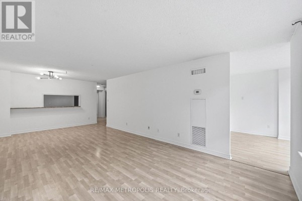 Empty living and dining room with light wood flooring and white walls. - 409 - 1485 Lakeshore Road E, Mississauga