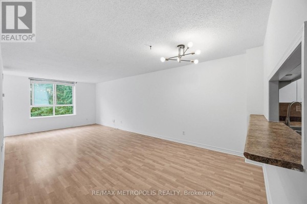 Living room with a large window overlooking trees and a granite countertop. - 409 - 1485 Lakeshore Road E, Mississauga