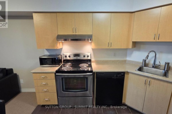 Kitchenette with light wood cabinets, stainless steel stove, and microwave. - 409 - 35 Saranac Boulevard, Toronto