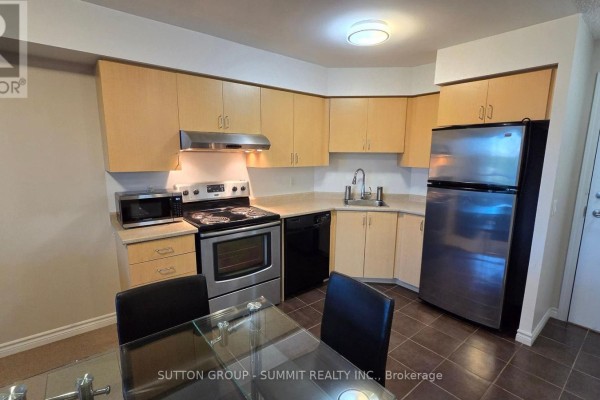 Corner kitchen with light wood cabinets, stainless steel refrigerator, and dining table with chairs. - 409 - 35 Saranac Boulevard, Toronto