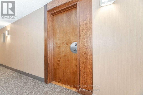 Wood-paneled apartment door with metal handle and number 409 at the end of a hallway. - 409 - 3880 Duke Of York Boulevard, Mississauga