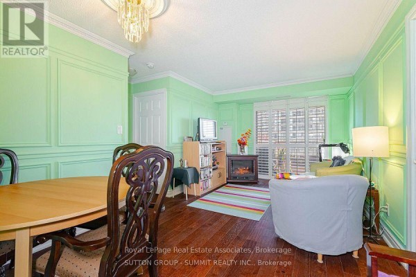 Living and dining area with wood floors, green walls, electric fireplace, and furniture. - 409 - 3880 Duke Of York Boulevard, Mississauga