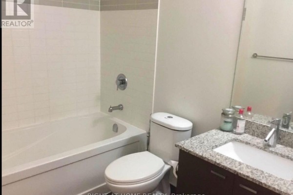 Bathroom with a white bathtub, toilet, granite countertop vanity, and a stainless steel faucet. - 409 - 88 Sheppard Avenue E, Toronto