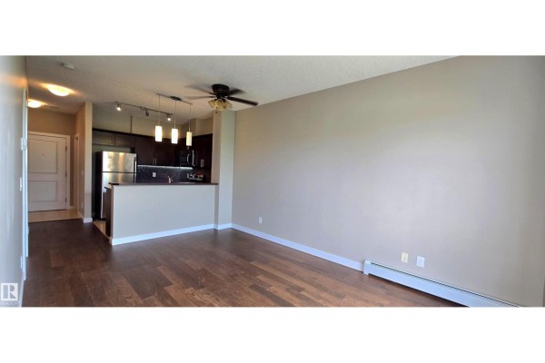 An open-concept living and dining area with dark hardwood floors and a view into the adjacent kitchen. - #409 2584 Anderson Wy Nw, Edmonton