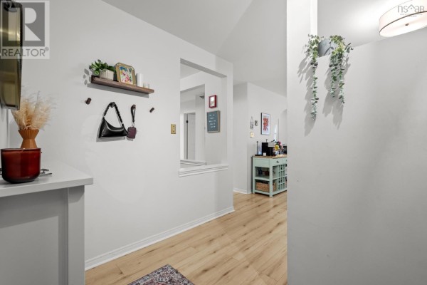 Hallway with light wood flooring, a floating shelf with decor, and an opening to the kitchen. - 409 93 Kearney Lake Road, Kearney Lake