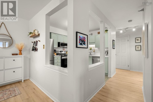 View of the kitchen through a decorative opening, showing light green cabinets and stainless steel appliances. - 409 93 Kearney Lake Road, Kearney Lake