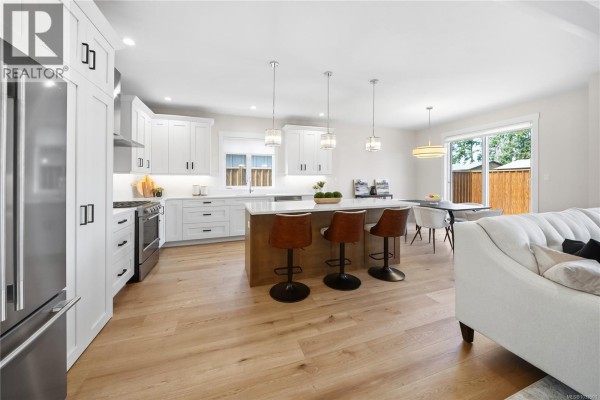 Long view of the backyard with a wooden fence, artificial turf, and trees. - 409 Hummingbird Pl, Parksville