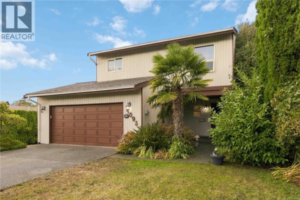 Close-up of the beige house entrance with a palm tree and garden. - 4095 Beam Cres, Saanich