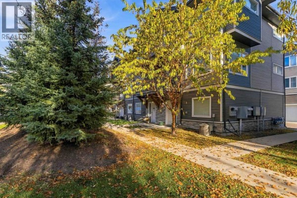 Exterior side view of a townhouse with dark grey siding and stone accents, next to trees. - 41, 141 Fontaine Crescent, Fort Mcmurray