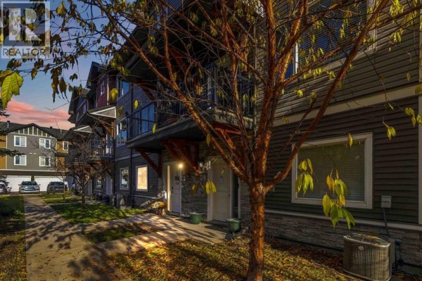 Exterior view of townhouses with balconies and entrance doors, lined by trees and a sidewalk. - 41, 141 Fontaine Crescent, Fort Mcmurray