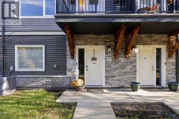 Close-up exterior view of townhouse entrances 41 and 42 with white doors and stone detailing. - 41, 141 Fontaine Crescent, Fort Mcmurray