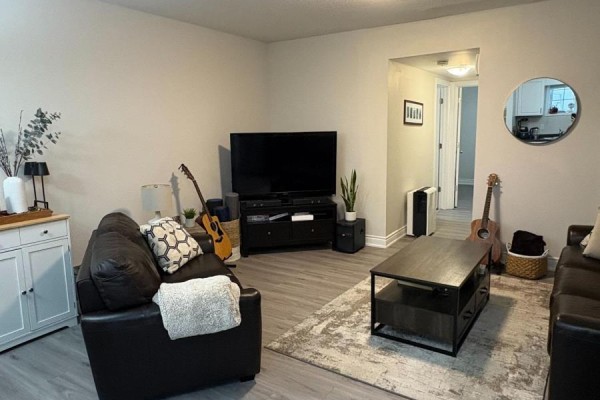 Living room with dark leather sofas, a television, coffee table, and light gray walls. - 41 - 3200 Singleton Avenue, London South