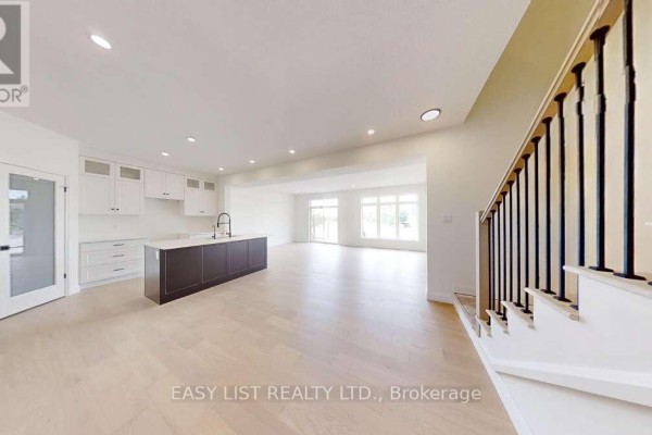 Open-concept living area with large windows, light wood flooring, and modern kitchen island. - 41 - 55 Teal Drive, Guelph