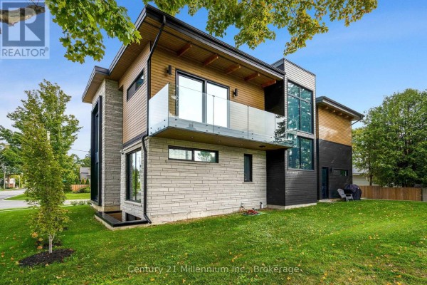 Rear view of the modern home showing a balcony with glass railings and a grassy lawn. - 41 Alice Street W, Blue Mountains