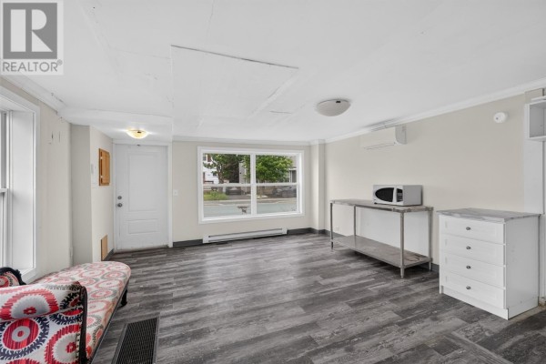 Interior living space with wood-look flooring, a window, and a microwave on a metal stand. - 41 Cashin Avenue, St John S