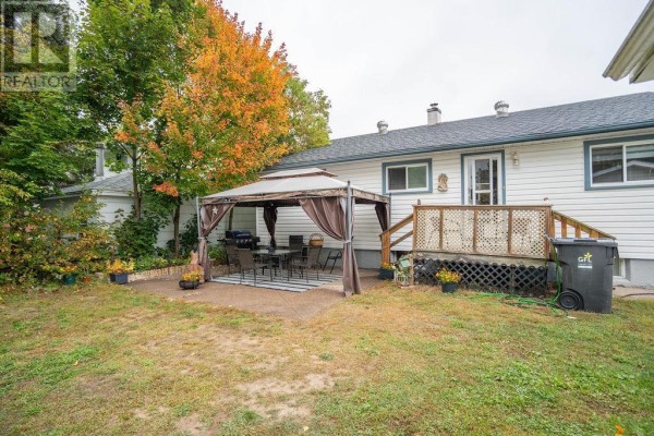 Backyard patio with a gazebo, table, chairs, and a wooden deck with railing and stairs. - 41 Centre St, Sault Ste  Marie
