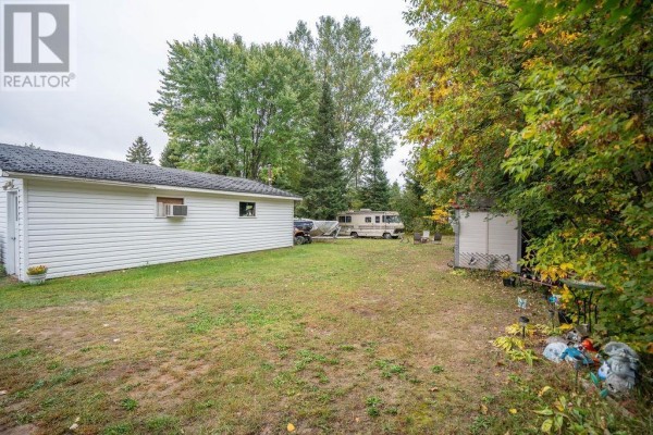 Backyard with a detached garage, RV, shed, and various yard decorations surrounded by trees. - 41 Centre St, Sault Ste  Marie