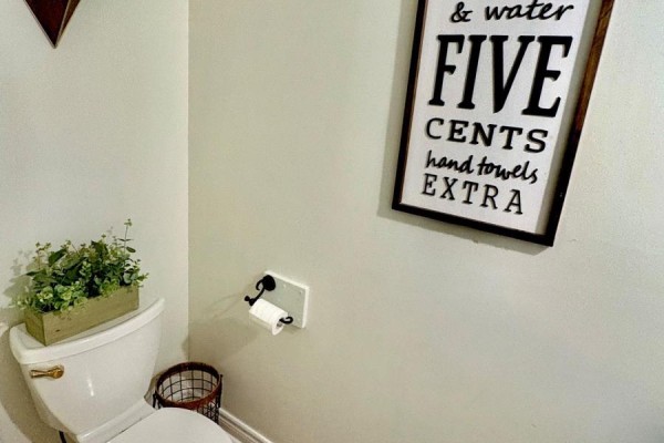 Powder room with a toilet, toilet paper holder, and decorative sign on the wall. - 41 David Street, Ingersoll