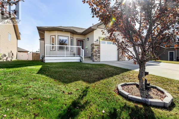Side exterior view of the duplex at 41 Ebony Street, Lacombe with a grassy lawn and a decorative tree. - 41 Ebony Street, Lacombe