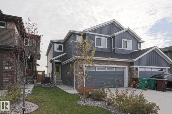 Side view of a duplex showing grey siding, stone accents, and a green front door. - 41 Elko Bn, St  Albert