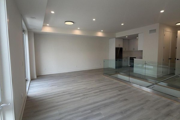 Open-concept living area with light gray wood-look flooring and a modern kitchen with white cabinets. - 41 Everett Common, St  Catharines