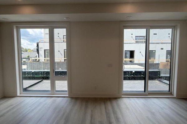 Living room with two large windows and a sliding glass door offering a view of adjacent buildings. - 41 Everett Common, St  Catharines