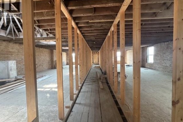 Interior view of unfinished commercial space with wooden studs and exposed ceiling beams. - 41 High Street W, Moose Jaw