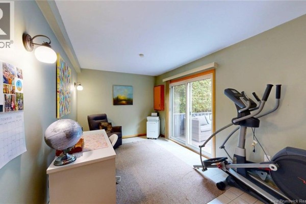 Home office with exercise equipment, desk, chair, and sliding glass doors to a deck. - 41 Hillsview Crescent, Rothesay
