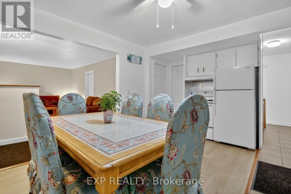 Dining table with upholstered chairs in front of a large window and a white refrigerator. - 41 Hwy 5 W Street, South Dundas
