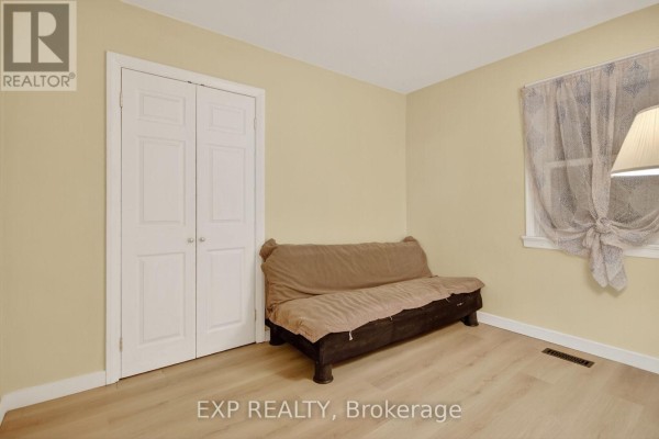Light yellow room with a futon and a double bi-fold closet door, with sheer curtains on the window. - 41 Hwy 5 W Street, South Dundas
