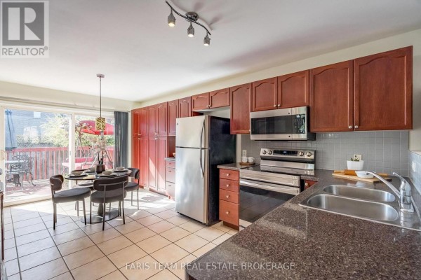 Kitchen and dining area with dark wood cabinets, stainless steel appliances, and a walk-out to a deck. - 41 Irene Drive, Barrie