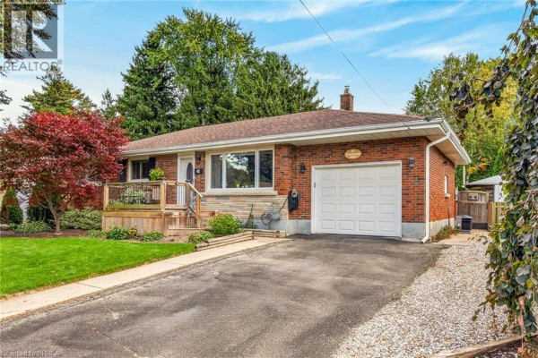 Side view of the brick bungalow, showing the driveway, garage door, and landscaping. - 41 Kensington Avenue, Brantford