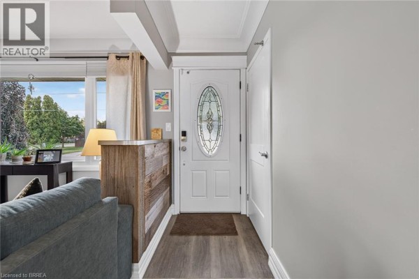 Interior view of the front entrance with a white door, grey walls, and wooden accents. - 41 Kensington Avenue, Brantford