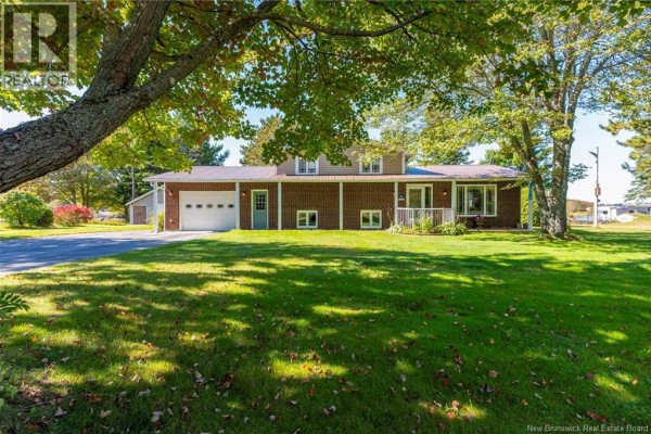 Wide exterior view of the house with a large green lawn and mature trees. - 41 Manuel, Baie Sainte Anne