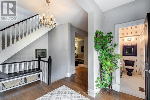 Interior foyer with double glass doors, hardwood floors, and a hallway leading to dark doors. - 41 Maple Street, Bancroft