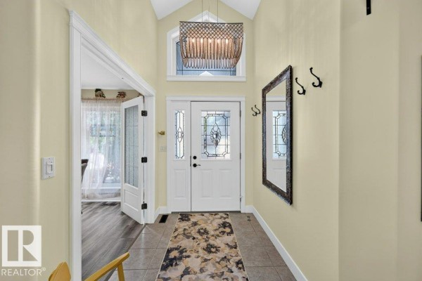 Foyer with tiled floor, double front doors, decorative mirror, and vaulted ceiling. - 41 North Ridge Dr, St  Albert